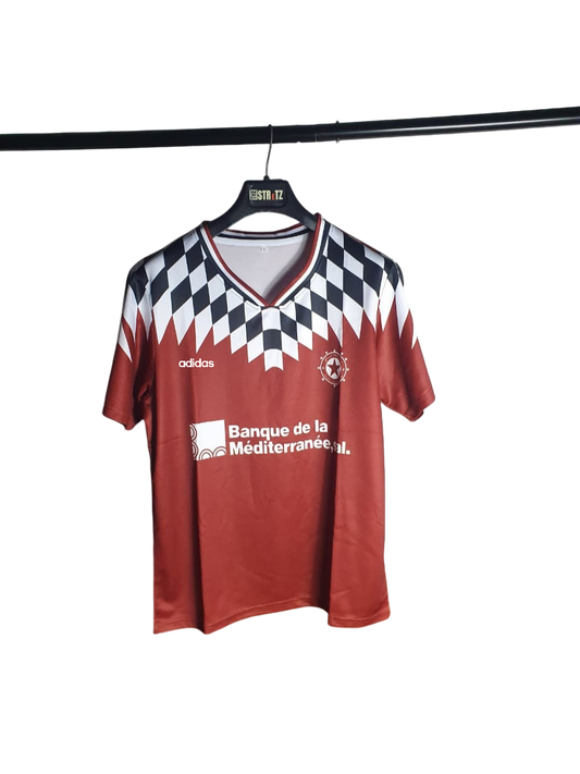 Red sports jersey with black and white checkered pattern on a hanger against a white background