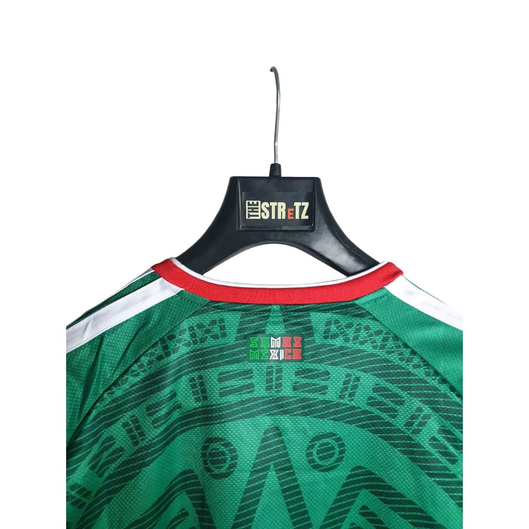 Green sports jersey with red collar on a hanger against a white background