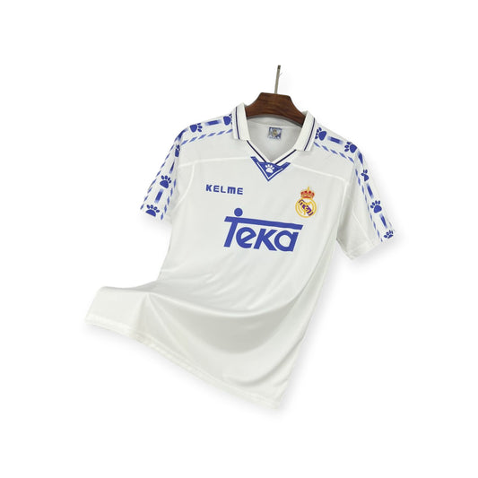 Real Madrid 1996/1997 Home Jersey displayed on a mannequin, predominantly white with blue accents and sponsor logo.