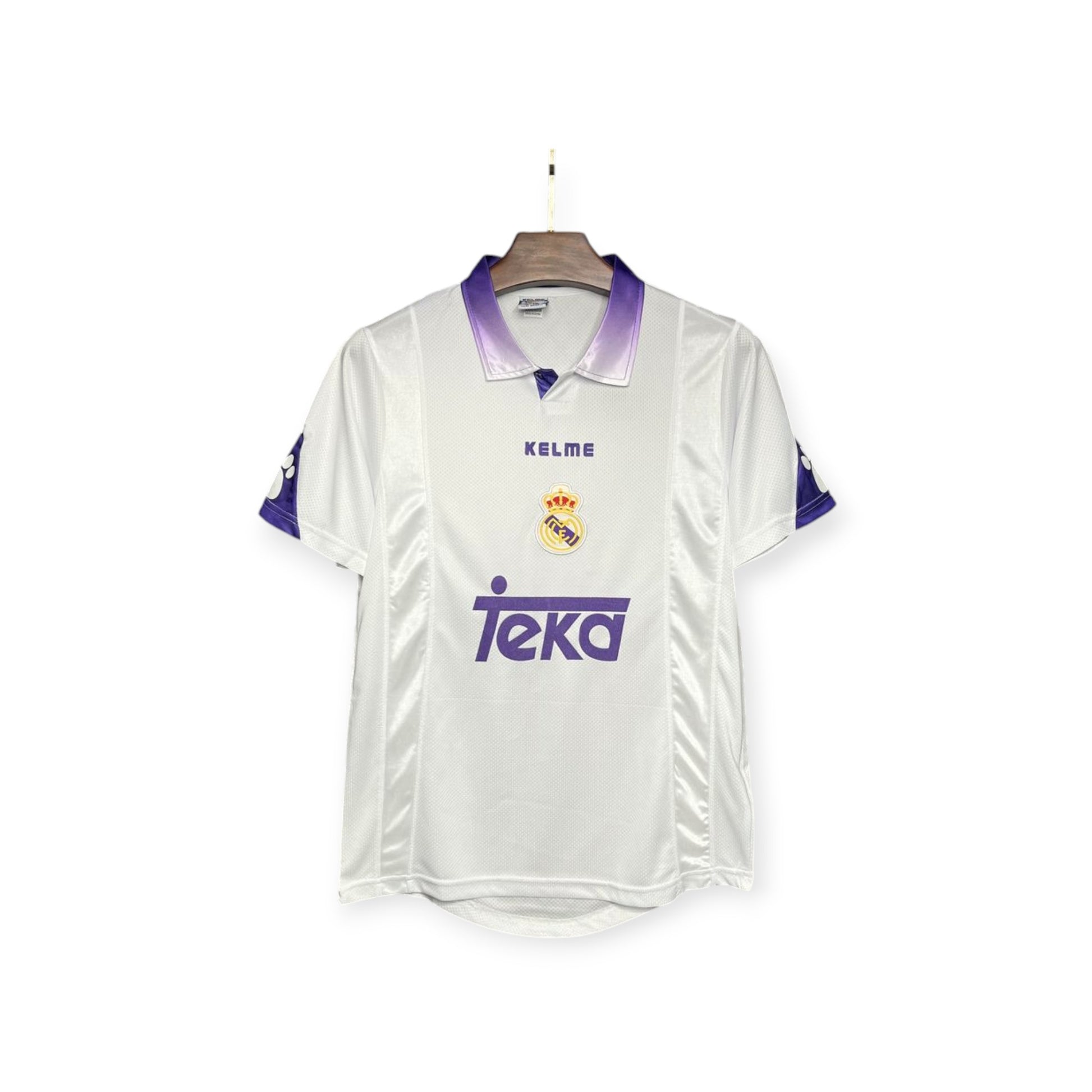 Real Madrid 1997/1998 home jersey displayed on a mannequin, predominantly white with purple accents, featuring the team's logo and a sponsor's logo.