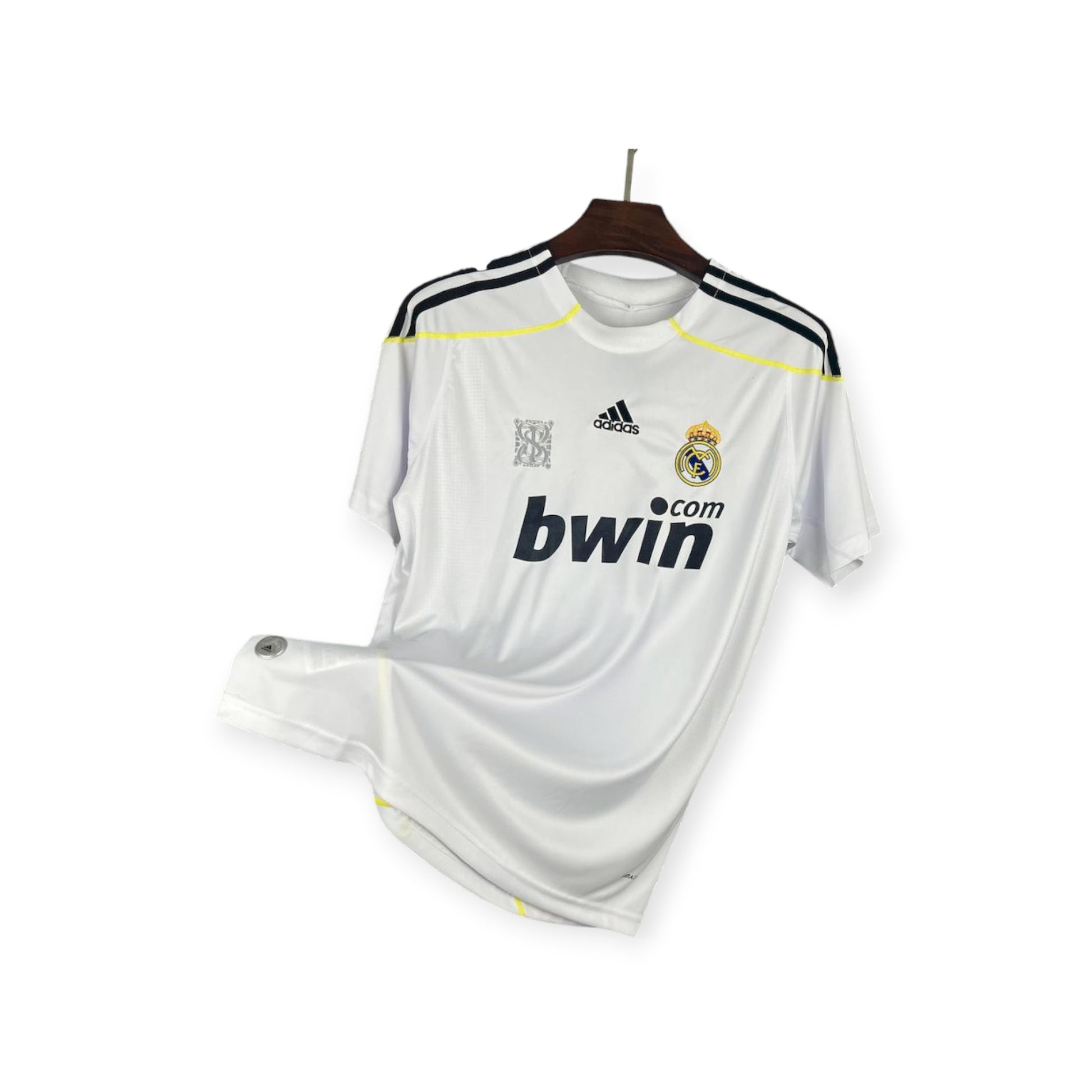 Real Madrid 2009/2010 Home Jersey displayed on a hanger, predominantly white with black and yellow accents, Adidas logo, and bwin.com sponsorship branding.