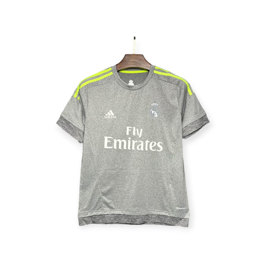 Real Madrid 2015/2016 Away Jersey displayed on a hanger, gray with yellow accents and 'Fly Emirates' text on the front.